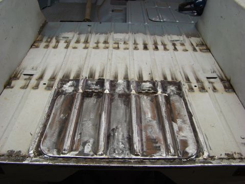 1948 Jeep Wrangler - The ribbed metal floor of a vehicle's interior shows signs of repair work, with numerous weld spots and some rust.