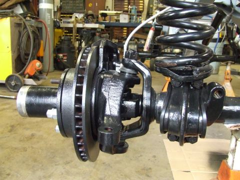 1967 Ford Bronco - Close-up of a vehicle's front axle assembly, a disc brake and suspension coil.