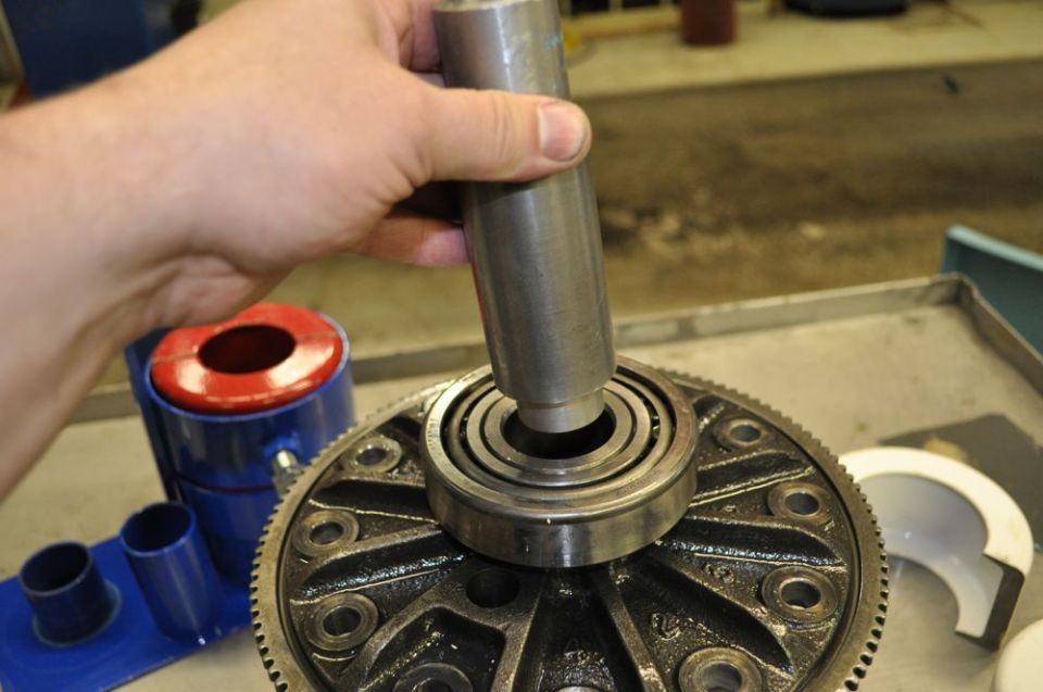Hand using a tool to install a bearing onto a differential gear