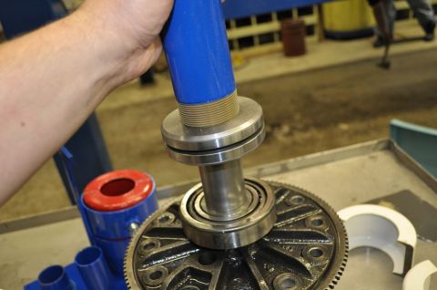 1996 Ford Bronco - A hand operates a bearing puller tool on a differential gear assembly in a workshop setting.