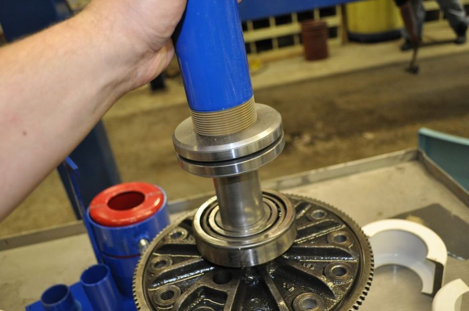 Bearing puller tool with blue handle over differential gear. Metal parts and red cap visible