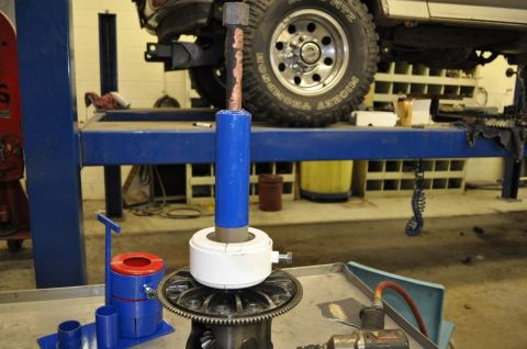 1996 Ford Bronco - A bearing puller tool is set up on a vehicle's differential, with a tire visible above.