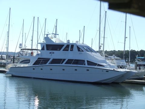 1976 Ford F-150 - A large white yacht is docked in a marina, surrounded by sailboats under a clear blue sky.