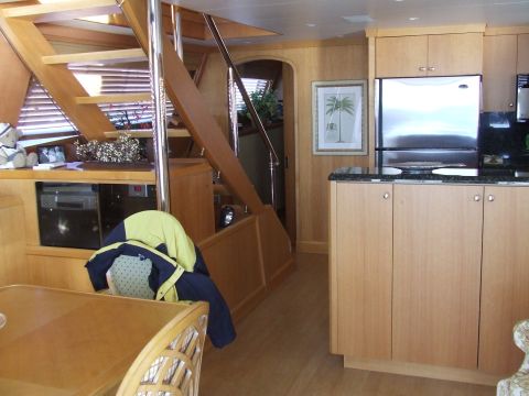 1976 Ford F-150 - Interior view of a boat or RV showing a kitchen area with a refrigerator and cabinets, adjacent to a wooden staircase.