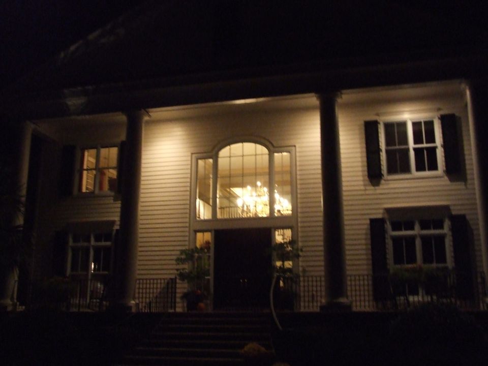 Large house with columns and large arched window at night