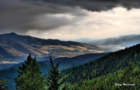 1996 Ford Bronco - A vast mountain valley is viewed under dramatic, cloudy skies with sunbeams piercing the haze.