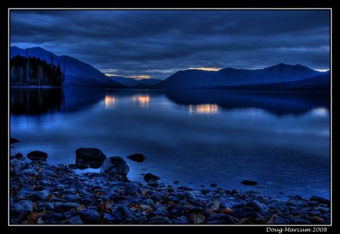1996 Ford Bronco - A lake scene at dusk, with mountains silhouetted against a dramatic sky and reflected in the still water.