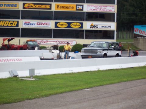 1995 Ford Bronco - A two-tone Ford F-Series truck is parked on a drag strip with a man standing nearby.