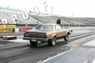 1995 Ford Bronco - A two-door coupe is on a drag strip with empty grandstands in the background.