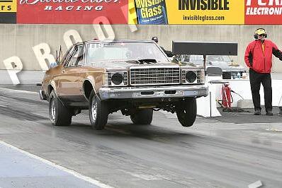 1995 Ford Bronco - A drag car launches off the line with its front wheels airborne.
