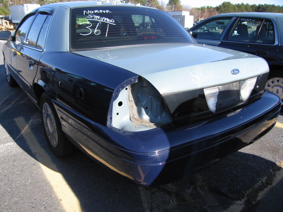 Rear view of a 2001 Ford Crown Victoria with the taillight assembly missing on the driver's side. Text on the rear window reads 'NORTER STRIPPED 361'