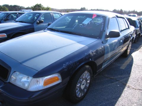 2001 Ford Crown Victoria - A blue and dark blue 2001 Ford Crown Victoria is parked in a lot with other vehicles.
