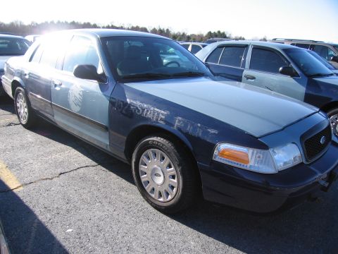 2001 Ford Crown Victoria - A 2001 Ford Crown Victoria police car is seen in a parking lot, with another police car visible behind it.