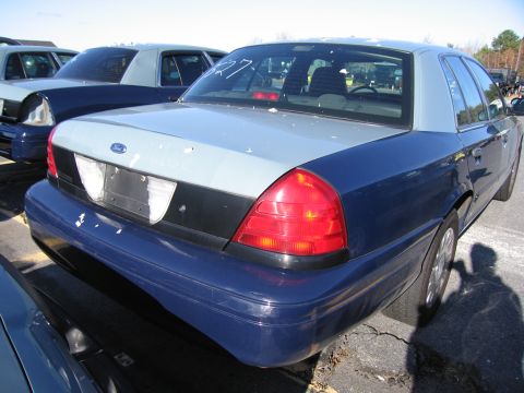 2001 Ford Crown Victoria - The rear of a two-tone Ford Crown Victoria is visible, parked in a lot with other vehicles.