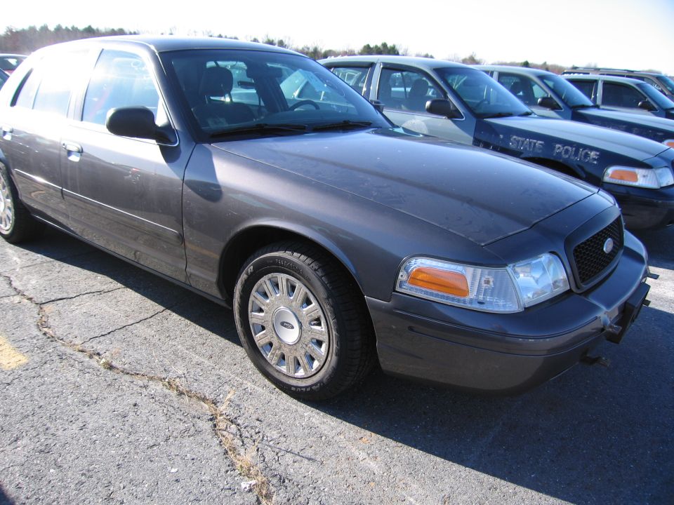 Dark gray 2001 Ford Crown Victoria, front passenger side, parked on cracked asphalt