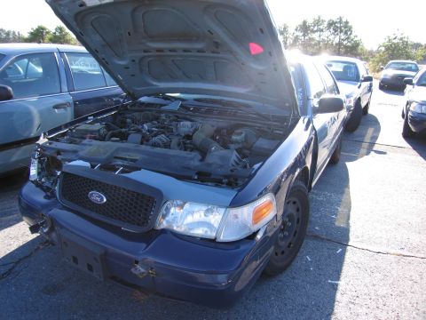 2001 Ford Crown Victoria - Front view of a 2001 Ford Crown Victoria with its hood open, parked next to another similar vehicle.
