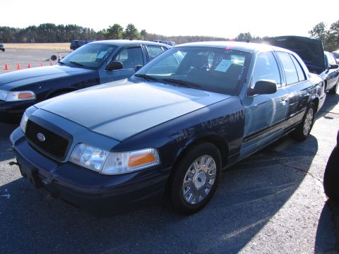 2001 Ford Crown Victoria - Two police sedans are parked in an outdoor lot. The front vehicle is a 2001 Ford Crown Victoria.