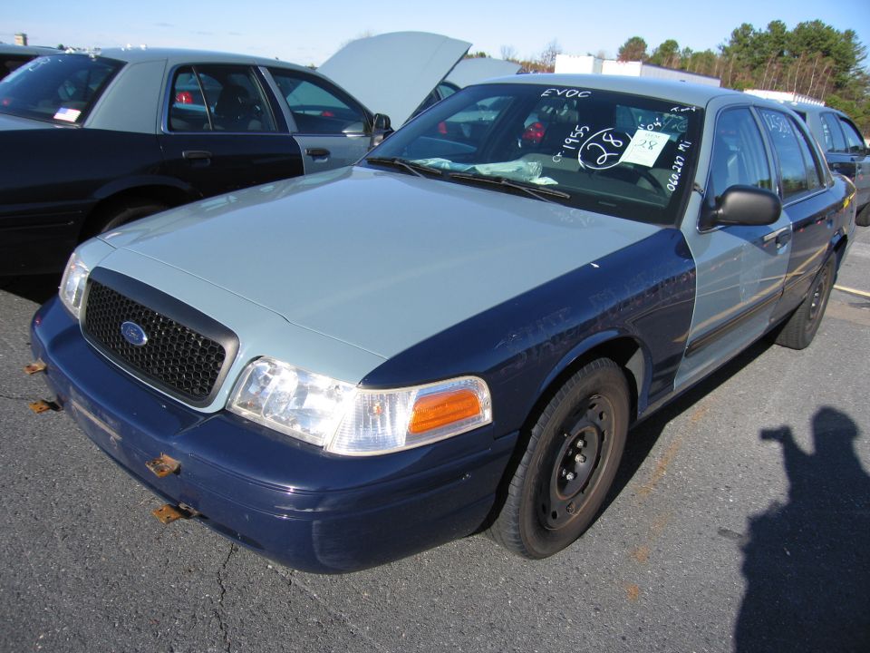 Two-tone Ford Crown Victoria, light blue hood and fenders, dark blue doors and rear. Hood is up on a car behind it