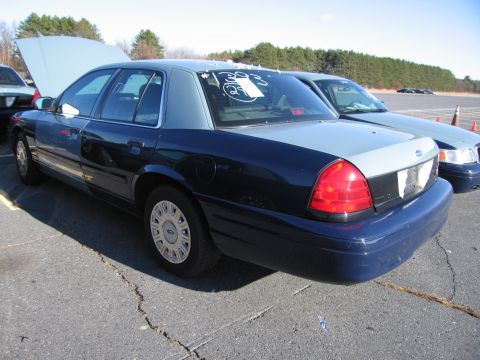 2001 Ford Crown Victoria - This 2001 Ford Crown Victoria sedan is shown from the rear quarter with its hood open, parked next to another vehicle.