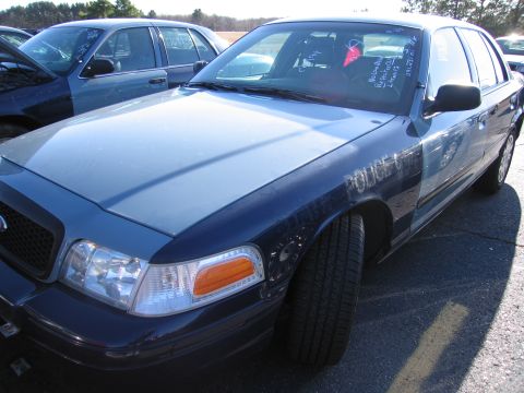 2001 Ford Crown Victoria - A police car is parked in a lot with another vehicle behind it.