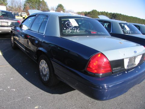 2001 Ford Crown Victoria - A dark blue and grey 2001 Ford Crown Victoria is parked in a lot with other vehicles, showing a sticker on its rear window.