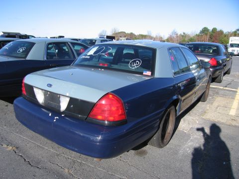 2001 Ford Crown Victoria - A blue and grey 2001 Ford Crown Victoria is parked in a lot with other vehicles, showing '40' and '02' markings on its rear window.