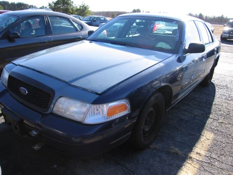 2001 Ford Crown Victoria - A blue Ford Crown Victoria is parked in an outdoor lot next to another vehicle.