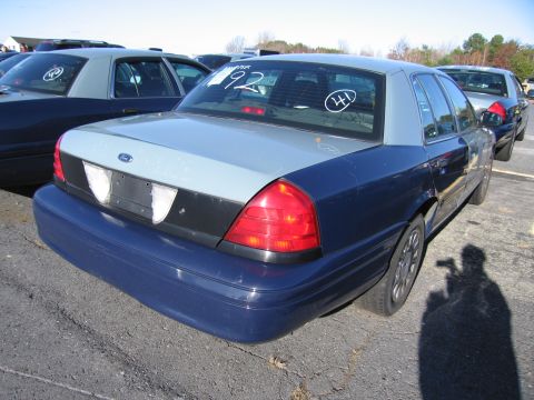 2001 Ford Crown Victoria - A blue and grey 2001 Ford Crown Victoria is parked in a lot with other vehicles.