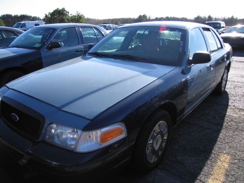 2001 Ford Crown Victoria - A 2001 Ford Crown Victoria is seen parked in a lot, with other vehicles in the background.