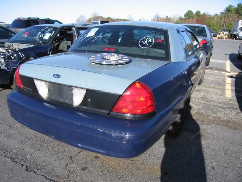 2001 Ford Crown Victoria - This Ford Crown Victoria, marked as a police vehicle, is parked in an outdoor lot with other cars.