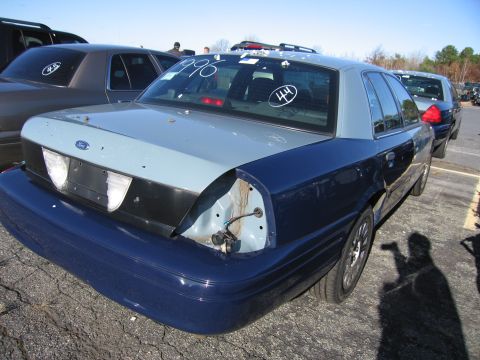 2001 Ford Crown Victoria - A two-tone Ford Crown Victoria is parked outdoors, showing damage to its rear passenger side.