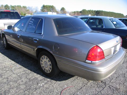2001 Ford Crown Victoria - A gray 2001 Ford Crown Victoria is parked in an outdoor lot with other vehicles, showing its rear 3/4 profile.