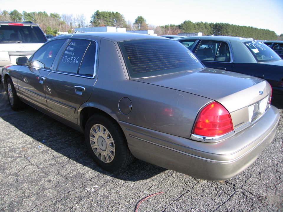 Gray 2001 Ford Crown Victoria, rear 3/4 view, parked in lot with other vehicles