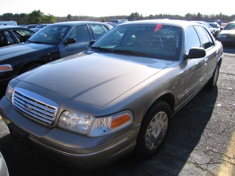 2001 Ford Crown Victoria - A tan 2001 Ford Crown Victoria is seen in a lot with other vehicles, markings on its windshield.