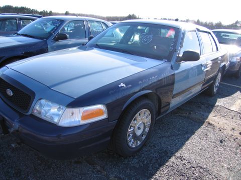 2001 Ford Crown Victoria - A two-tone police car sits in a lot, with other vehicles visible in the background.