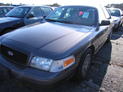 2001 Ford Crown Victoria - A dark gray 2001 Ford Crown Victoria is parked in a lot with other vehicles visible.