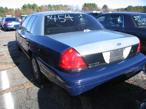 2001 Ford Crown Victoria - The rear of a two-tone Ford Crown Victoria is shown in a parking lot with other vehicles.