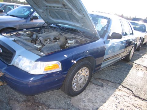 2001 Ford Crown Victoria - A blue and light blue 2001 Ford Crown Victoria is parked with its hood open, alongside other vehicles.