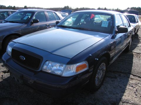 2001 Ford Crown Victoria - A blue Ford Crown Victoria is parked in a lot with other vehicles. A sticker with the number 63 is visible on the windshield.