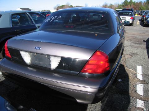 2001 Ford Crown Victoria - Rear view of a 2001 Ford Crown Victoria, showing its taillights and trunk lid. The vehicle is parked in an outdoor lot.