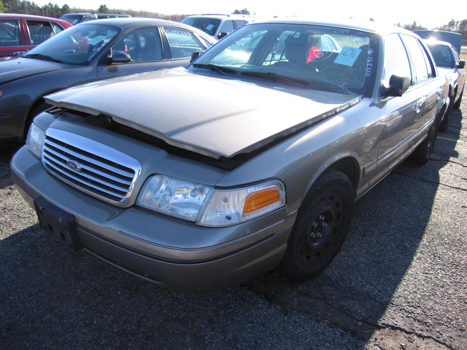 Front 3/4 view of a tan 2001 Ford Crown Victoria with its hood up. Other cars are parked nearby