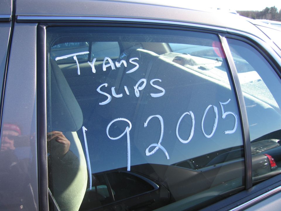 Gray car side window with white text 'TRANS SLIPS 192005' written on it