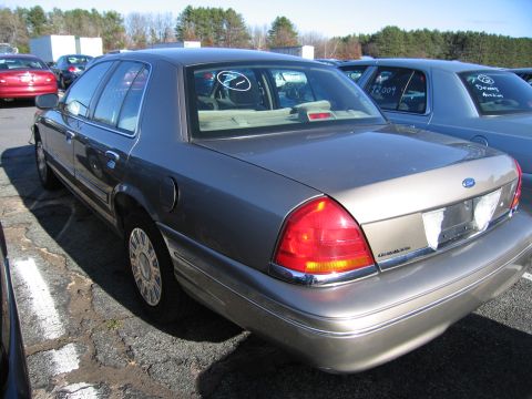 2001 Ford Crown Victoria - Rear quarter view of a gray Ford Crown Victoria parked in an outdoor lot with other vehicles.