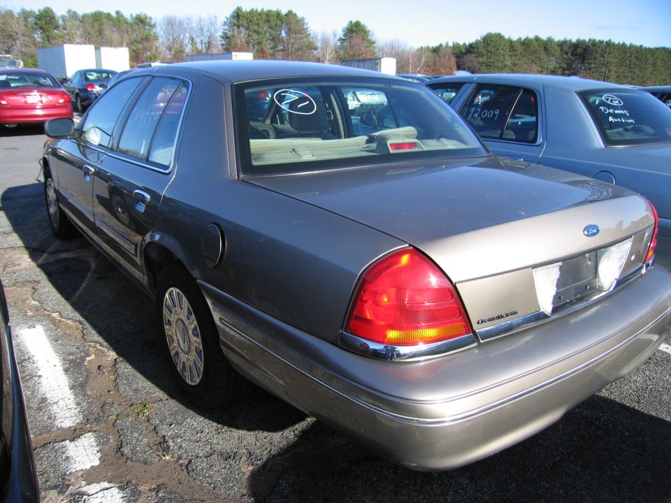 Gray Ford Crown Victoria parked in a lot. Another car is visible to the right