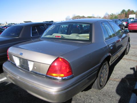 2001 Ford Crown Victoria - A tan 2001 Ford Crown Victoria is parked in a lot with other vehicles.