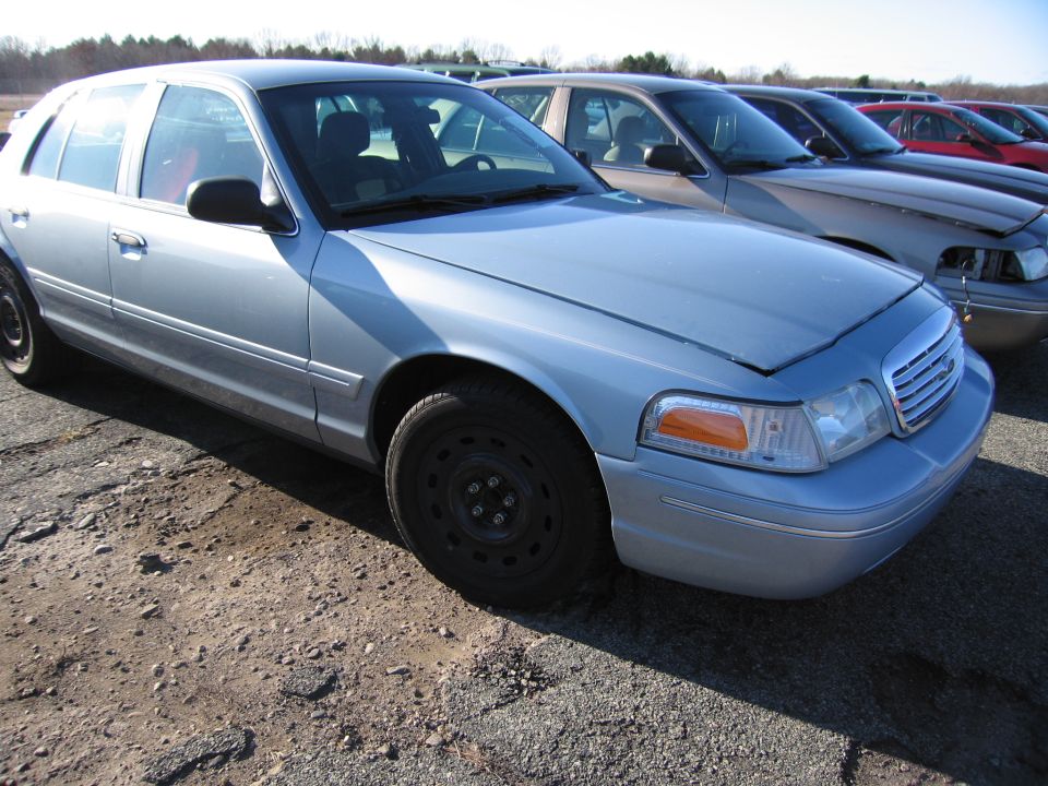Light blue 2001 Ford Crown Victoria parked in a lot with other cars behind it