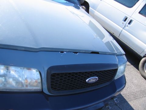 2001 Ford Crown Victoria - Front view of a blue 2001 Ford Crown Victoria showing its grille and headlights, with a white van visible to the right.