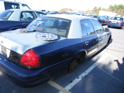 2001 Ford Crown Victoria - This 2001 Ford Crown Victoria is missing its wheels and has two hubcaps placed on its trunk.