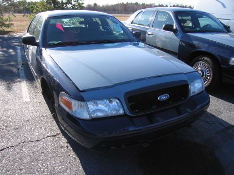 2001 Ford Crown Victoria - Front view of a 2001 Ford Crown Victoria parked outdoors next to another similar vehicle.