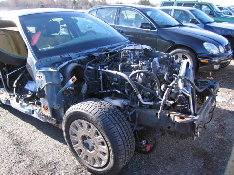 2001 Ford Crown Victoria - The front end of a 2001 Ford Crown Victoria is shown, stripped down to its chassis and engine, with other vehicles in the background.